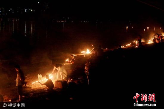 地处珠江上游的广西柳州市融江两岸群众把纸钱,衣物等物品,用写好逝去