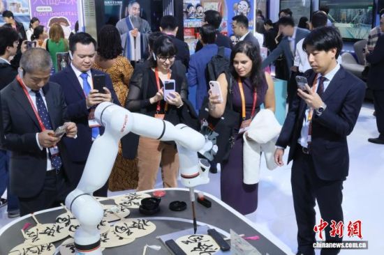 10月16日,第十届中国国际版权博览会在山东青岛举行。图为与会嘉宾驻足山东展区观看机械臂书写毛笔字。张孝鹏 摄 10月16日,第十届中国国际版权博览会在山东青岛举行。图为与会嘉宾驻足山东展区观看机械臂书写毛笔字。张孝鹏 摄