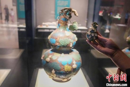 资料图:游客手持“珐琅镶玉葫芦”文创产品与河南博物院馆藏文物对比。 中新社记者 范晓恒 摄 资料图:游客手持“珐琅镶玉葫芦”文创产品与河南博物院馆藏文物对比。 中新社记者 范晓恒 摄