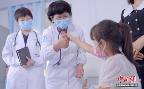 韩玉玲(左二)查房时,与患儿互动,帮助孩子建立战胜疾病的信心。(资料图,医院供图) 韩玉玲(左二)查房时,与患儿互动,帮助孩子建立战胜疾病的信心。(资料图,医院供图)